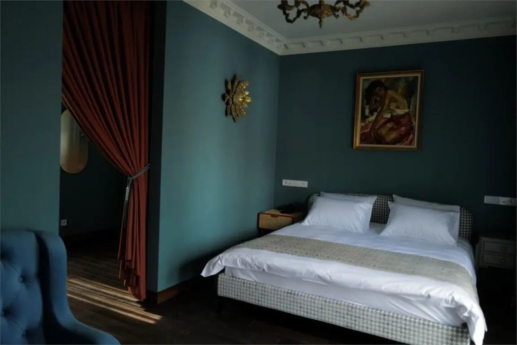 Elegantes Zimmer mit Doppelbett, blauen Wänden und Kunstdekoration