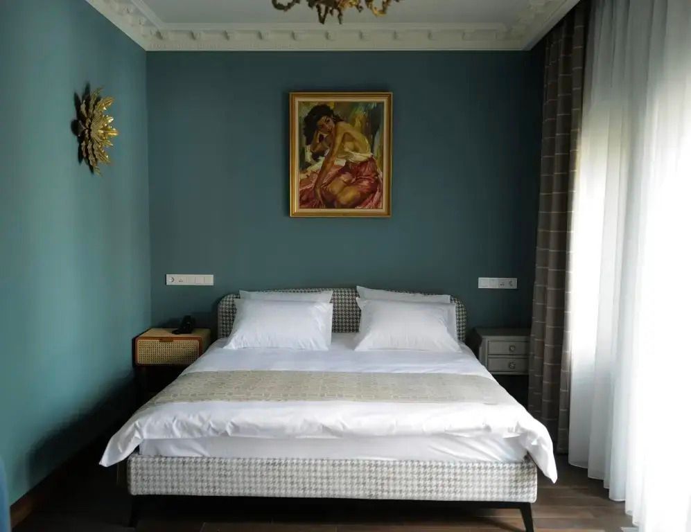 Doppelbett in elegantem Zimmer mit blauen Akzenten und Kunstwerk