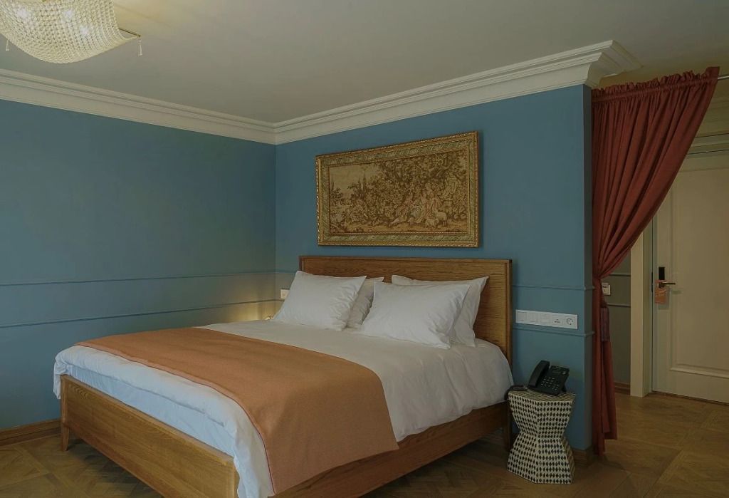 Gemütliches Doppelzimmer mit blauem Anstrich und kunstvollem Wandteppich