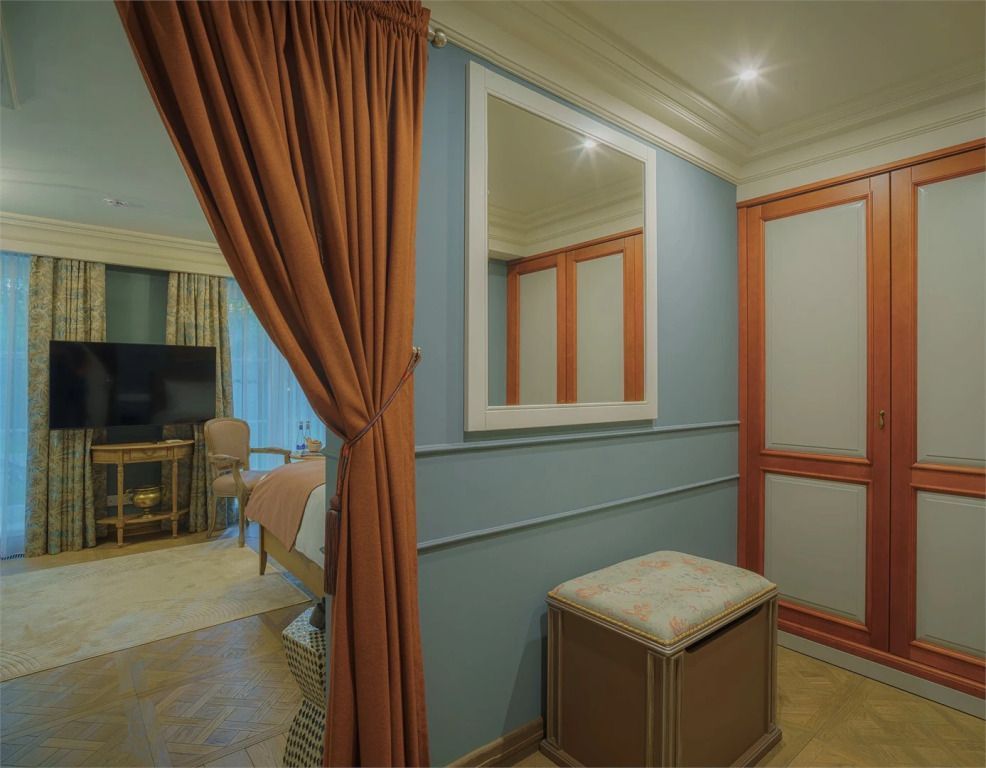Elegantes Hotelzimmer mit Vorhängen, Spiegel und Sitzgelegenheit