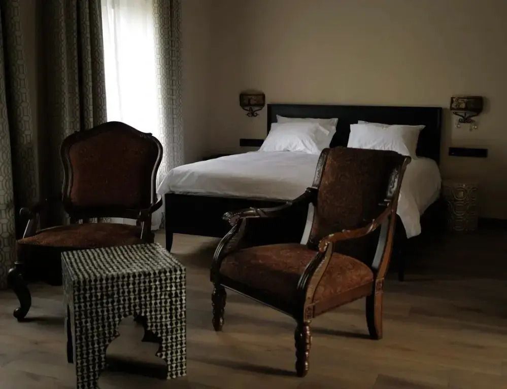 Gemütliche Sitzecke mit antiken Stühlen neben dem Doppelbett