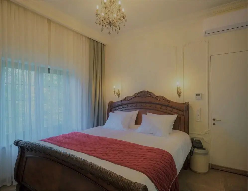 Elegantes Doppelbett in einer Suite mit Kronleuchter und Vorhängen