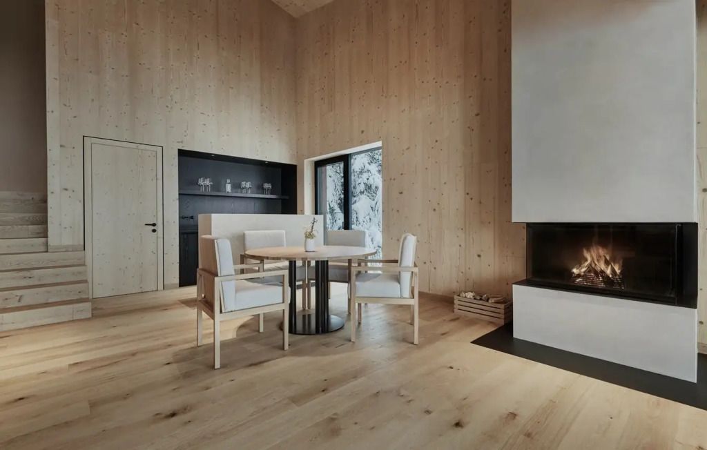 Gemütliche Sitzecke mit Holzwänden und Kamin in einer eleganten Suite