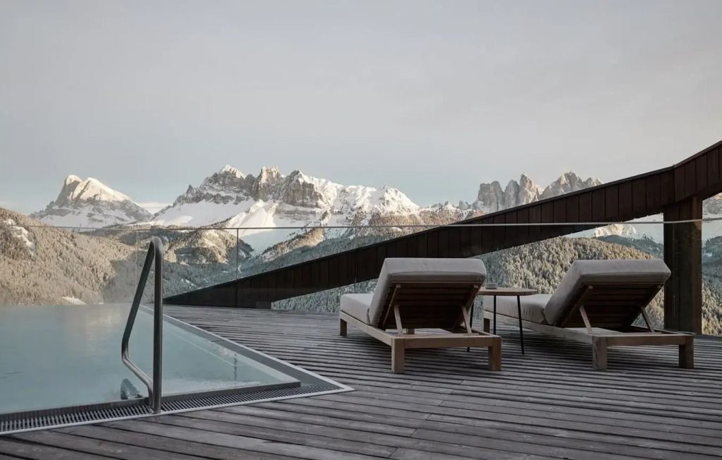 Terrasse mit Liegestühlen und Blick auf verschneite Berggipfel im Hintergrund