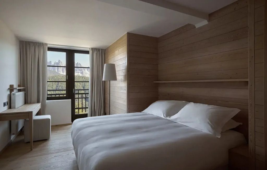 Helles Zimmer mit Doppelbett und Holzvertäfelung im Forestis Dolomites