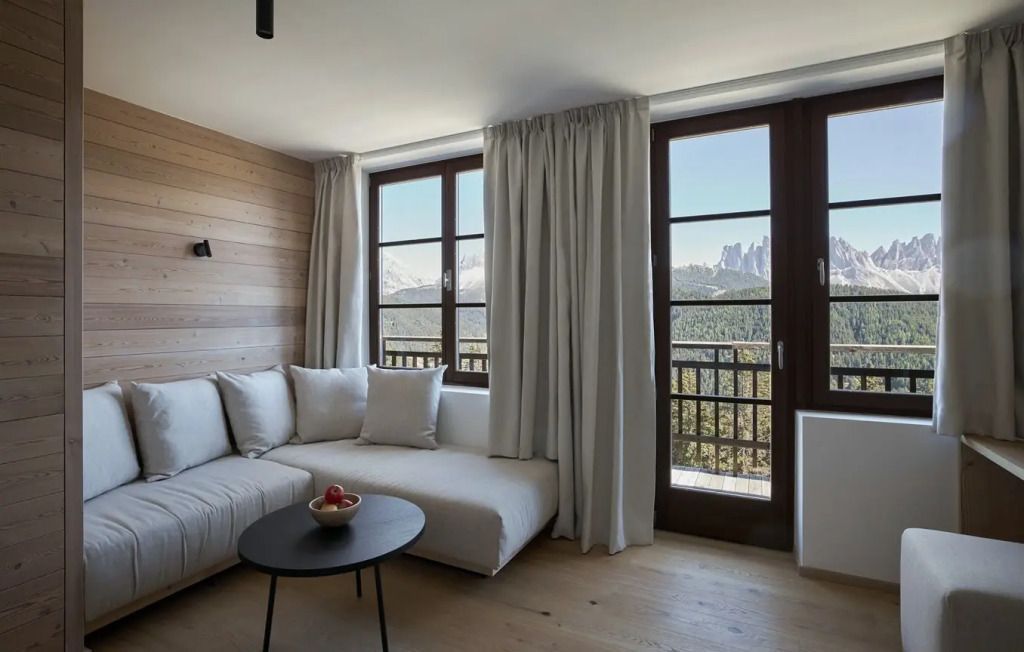 Wohnbereich mit Sofa und Panoramafenster mit Blick auf die Dolomiten