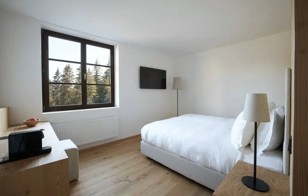 Helles Hotelzimmer mit großem Fenster, eingebautem Fernseher und Doppelbett