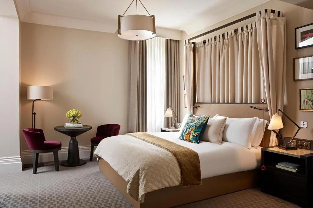Elegantes Zimmer mit großem Bett, Vorhängen und einem gemütlichen Sitzbereich