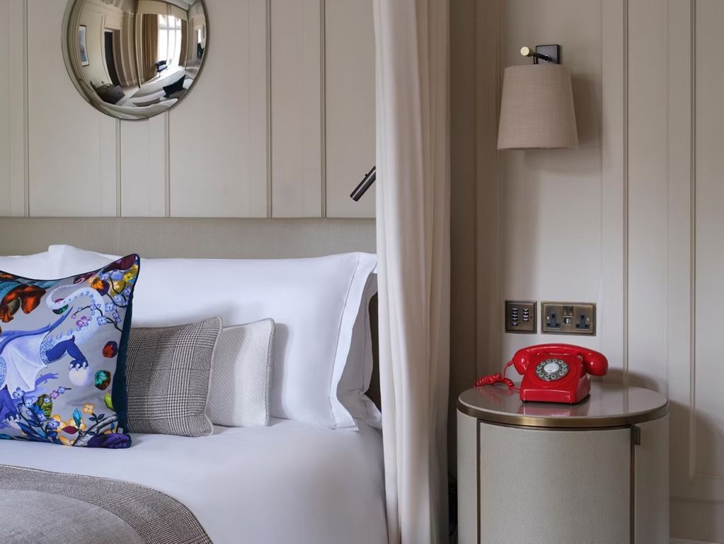 Stilvolles Schlafzimmer mit einem klassischen Telefon und bunten Kissen im Kimpton Fitzroy London.