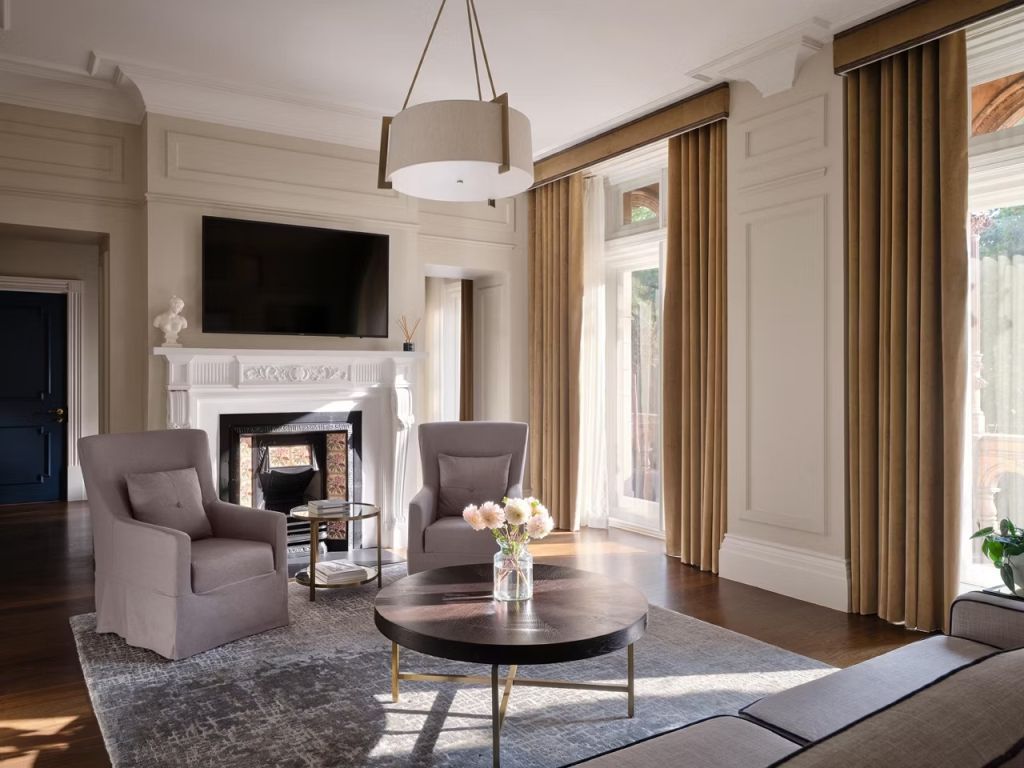 Eleganter Wohnbereich mit Kamin und Sesseln in der Fitzroy Doppel Suite im Kimpton Fitzroy London.