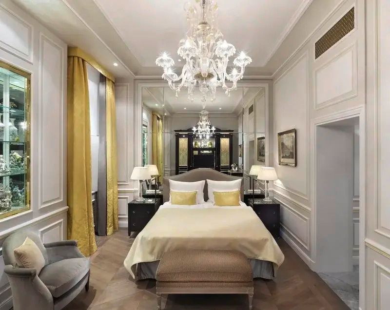 Elegantes Schlafzimmer mit gelben Akzenten und Kronleuchter.
