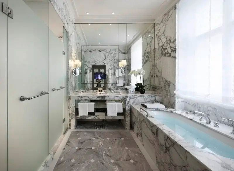 Luxuriöses Badezimmer in Marmoroptik mit Badewanne.