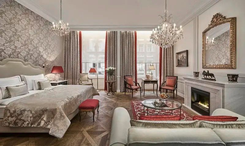 Elegantes Hotelzimmer mit Kronleuchter, Doppelbett, klassischen Möbeln und Kamin
