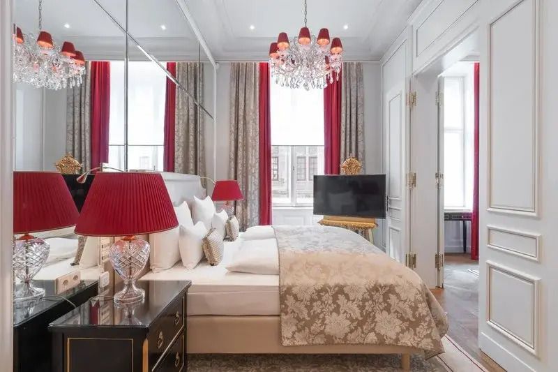 Elegantes Schlafzimmer der Madame Butterfly Suite mit Kronleuchter und roten Akzenten