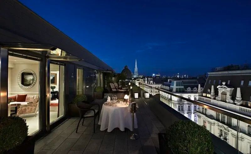 Nächtlicher Blick von der beleuchteten Terrasse mit Essbereich des Hotel Sacher Wien über Wien.