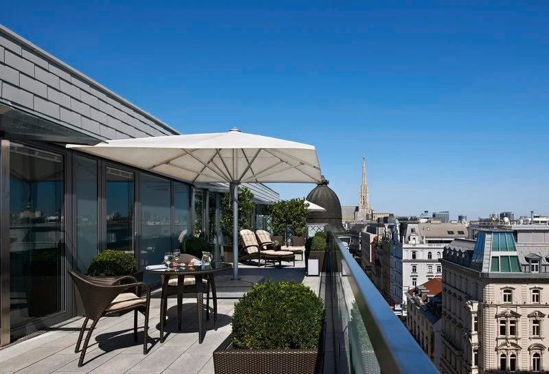 Sonnige Terrasse mit Sitzgelegenheiten und Blick auf den Wiener Stephansdom im Hotel Sacher Wien.