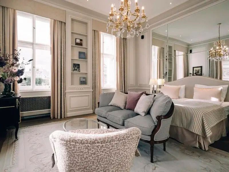 Geräumige Suite mit Sofa, Sesseln, Kristallleuchter und großen Fenstern