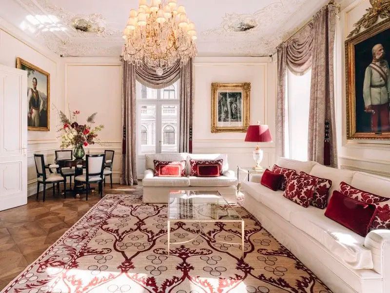 Geräumiges Wohnzimmer mit Sofas, Teppich und prunkvollem Kronleuchter.