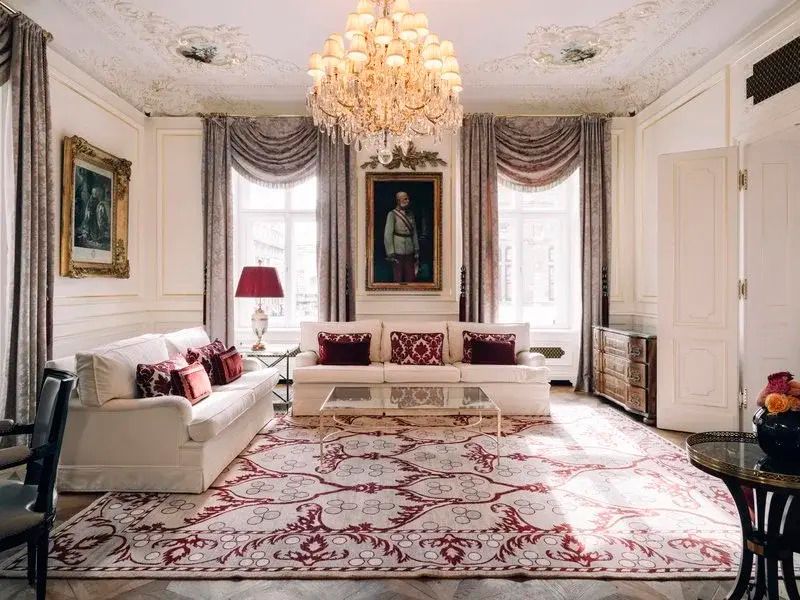 Luxuriöses Wohnzimmer mit Sofa, Gemälde und opulentem Kronleuchter.
