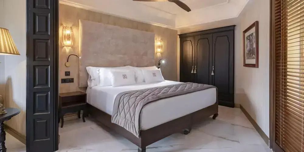 Luxuriöse Suite mit Kingsize-Bett, eleganter Beleuchtung und edlem Holzmöbel.