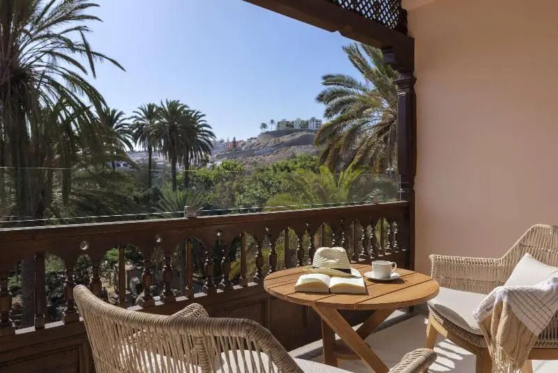 Balkon mit Blick auf Palmen und Tisch mit Kaffeetasse und Buch