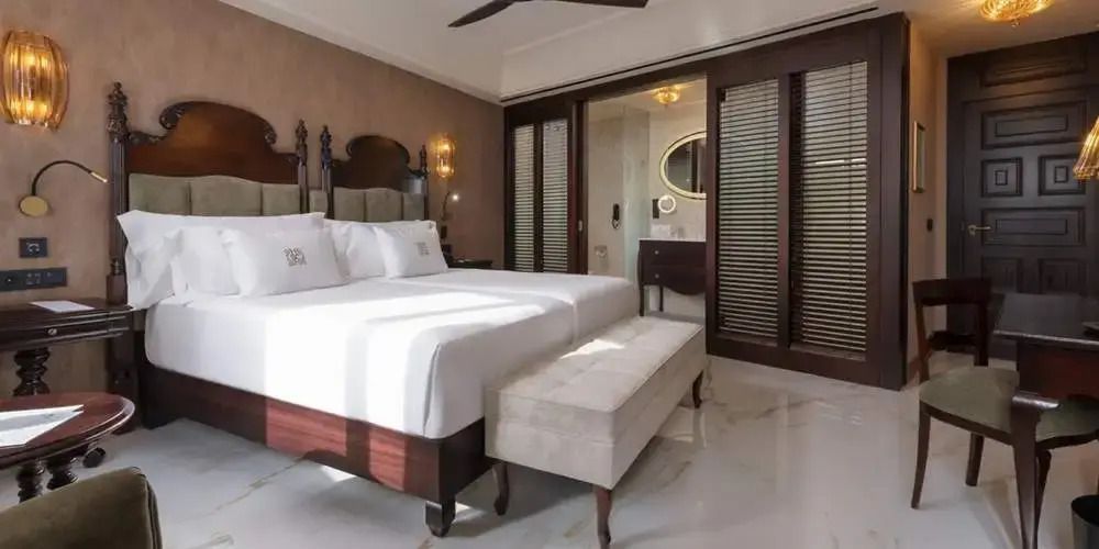 Junior-Suite mit zwei Einzelbetten und luxuriösem Bad im Hintergrund