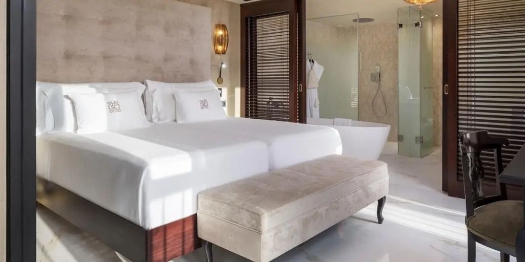 Helle Suite mit zwei Einzelbetten, edlem Polsterhocker und moderner freistehender Badewanne