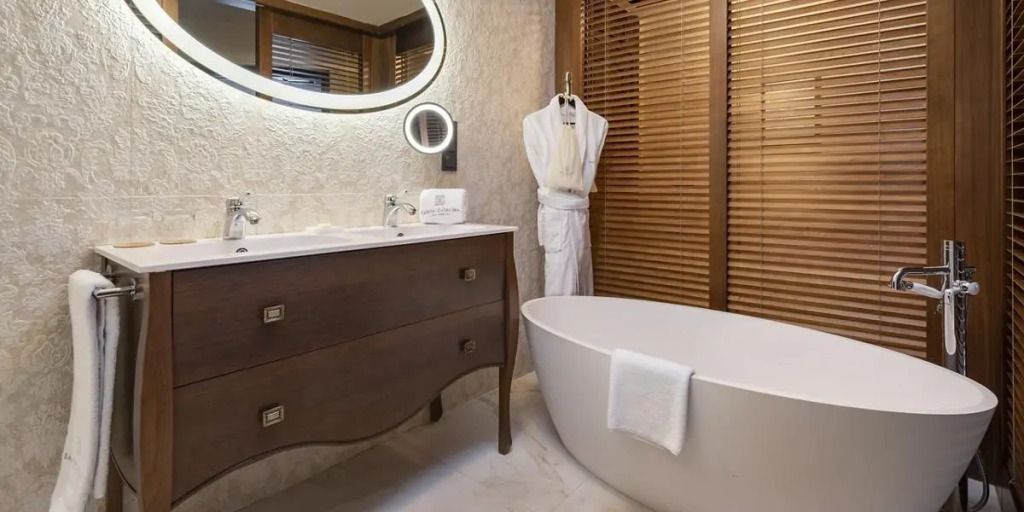 Modernes Bad mit freistehender Badewanne, eleganter Kommode und flauschigem Bademantel