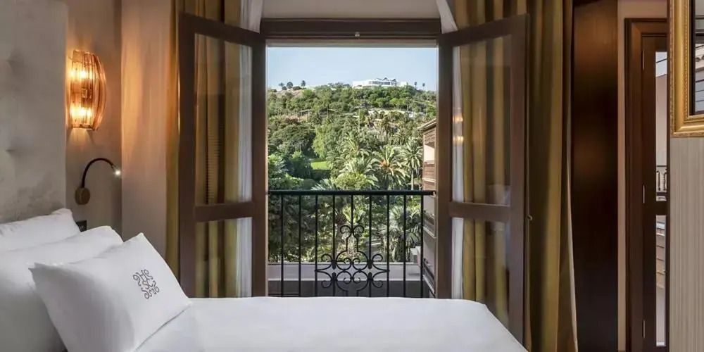 Ausblick von einem Zimmer auf grüne Landschaft mit Palmen und Hügeln