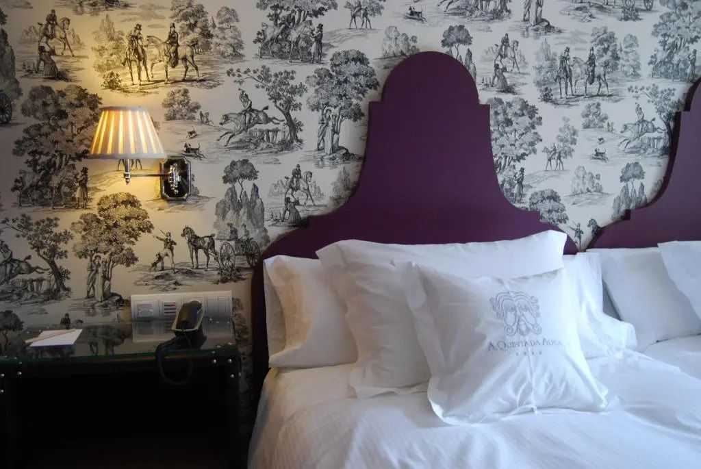 Elegantes Bett mit lila Kopfteil und kunstvoller Tapete im Deluxe Doppelzimmer