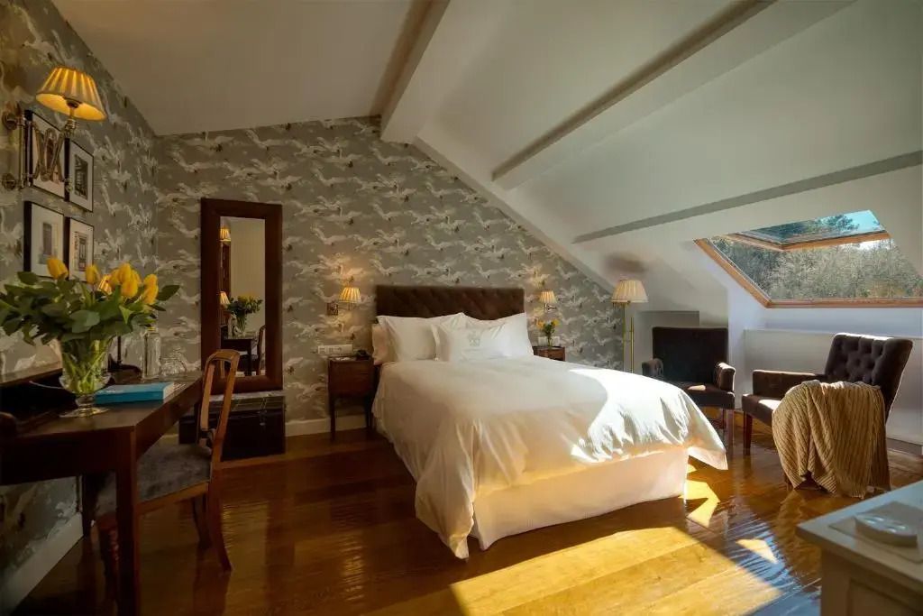 Klassisches Dachzimmer mit elegantem Dekor und Doppelbett im Hotel A Quinta da Auga