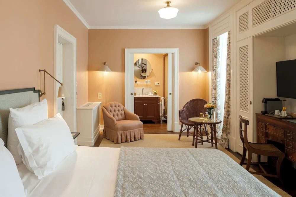 Geräumiges Zimmer mit Doppelbett, gemütlicher Sitzecke und Blick ins Badezimmer.