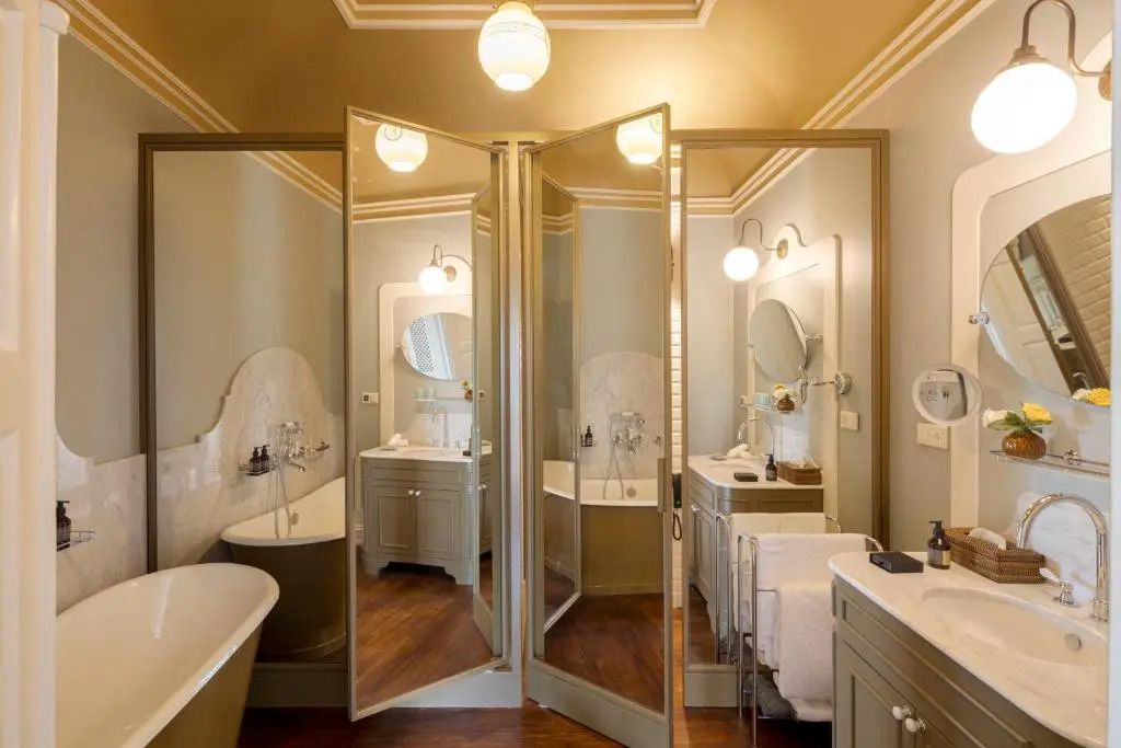 Elegantes Badezimmer mit großen Spiegeln, freistehender Badewanne und Waschtischen.