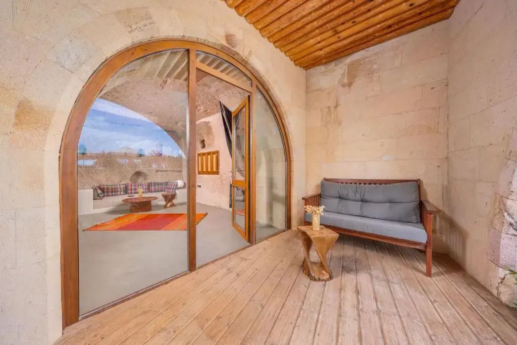 Holzveranda mit Sitzbank und Blick in die Höhlensuite mit elegantem Interieur