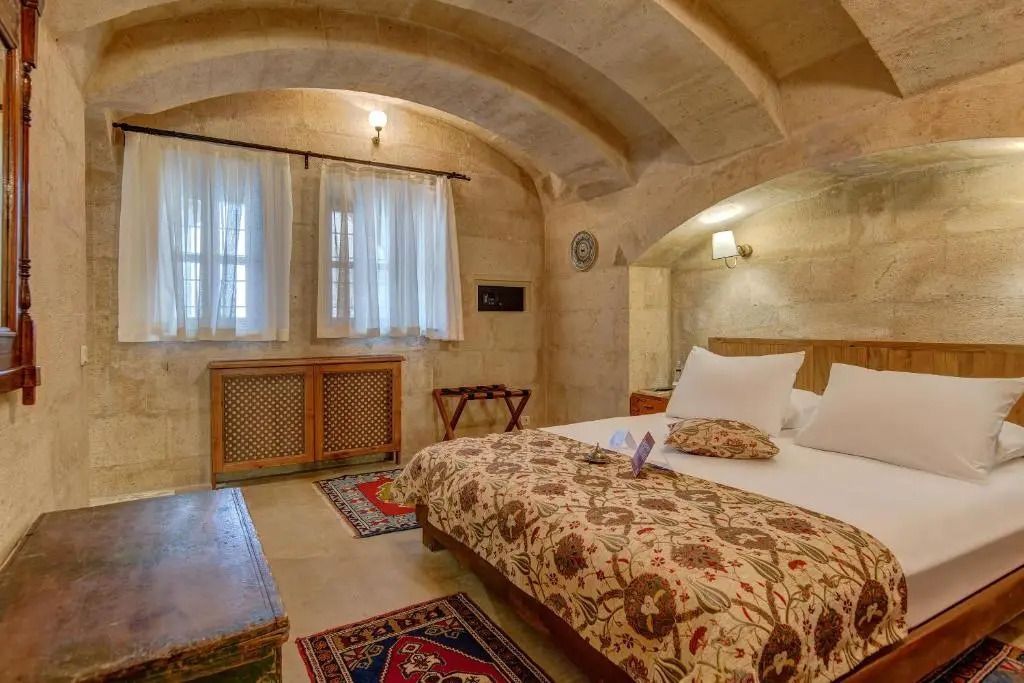 Komfortables Schlafzimmer mit Steinmauern, gemütlichem Bett und dekorativem Teppich