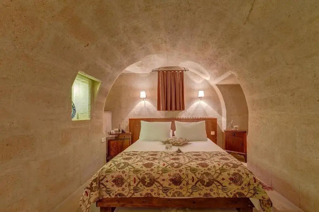 Gemütliche Suite mit Steinwänden und einem großen Doppelbett in Höhlenoptik