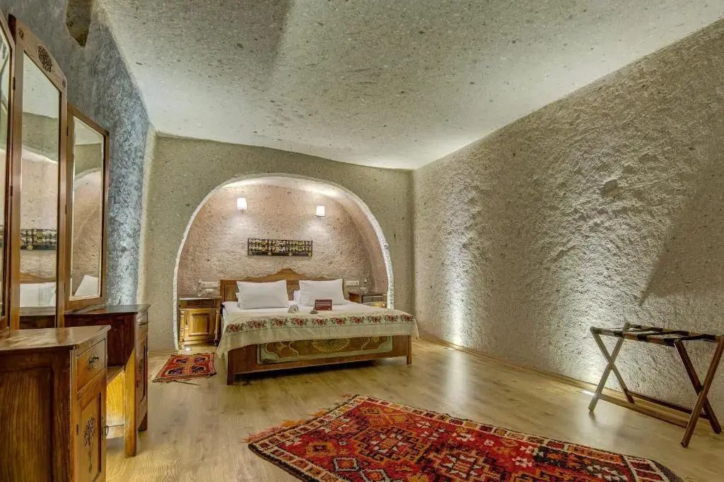 Stilvolles Schlafzimmer in einer Höhle mit orientalischen Teppichen und Holzbett