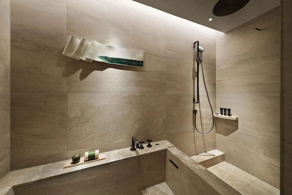 Moderne Regendusche in einem eleganten Bad mit Natursteinwänden