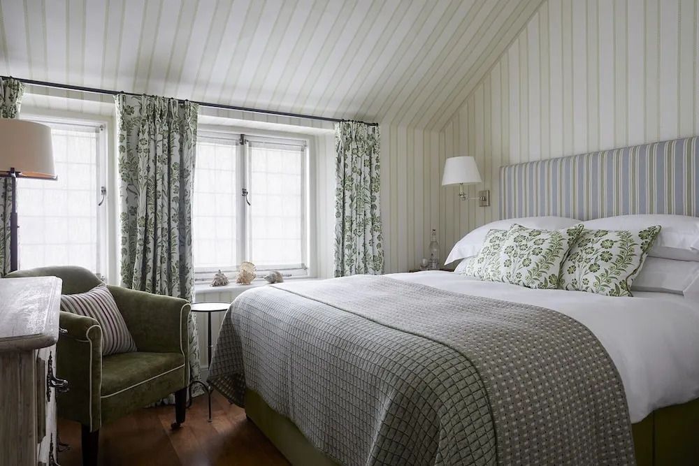 Gemütliches Doppelzimmer mit Fenster und grünem Sessel