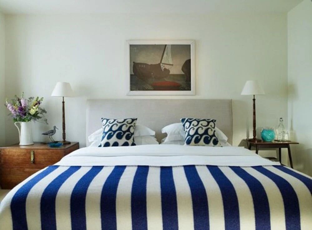 Doppelbett mit blauer gestreifter Decke und dekorativen Kissen