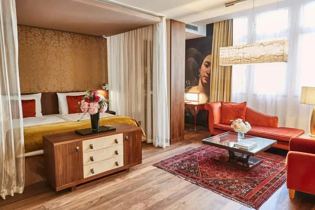 Komfortable Junior-Suite mit luxuriösem Bett, Teppich, Kunstwerken und moderner Einrichtung.