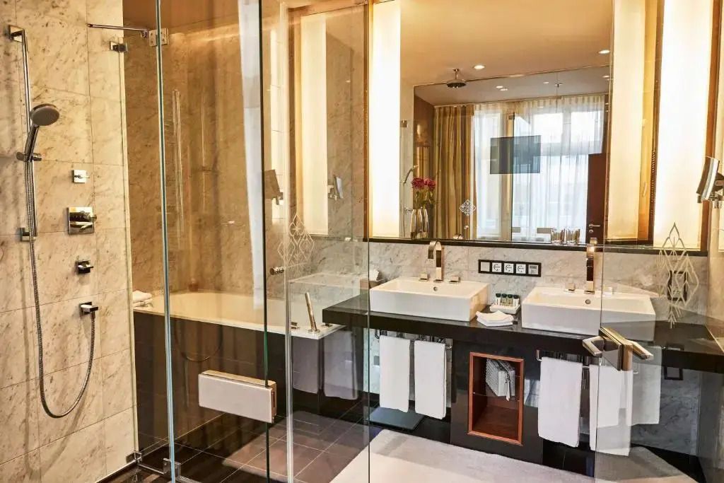 Modernes Badezimmer mit Glasdusche, Doppelwaschbecken und eleganter Marmoreinrichtung.