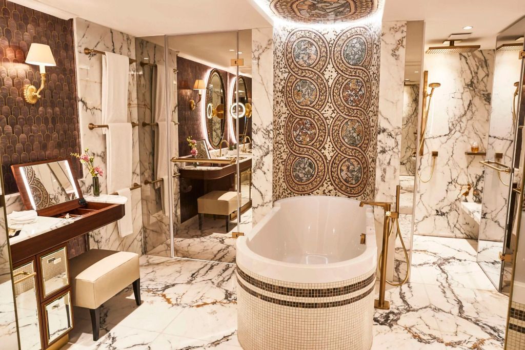 Luxuriöses Badezimmer der Suite mit freistehender Badewanne und Marmorverkleidung