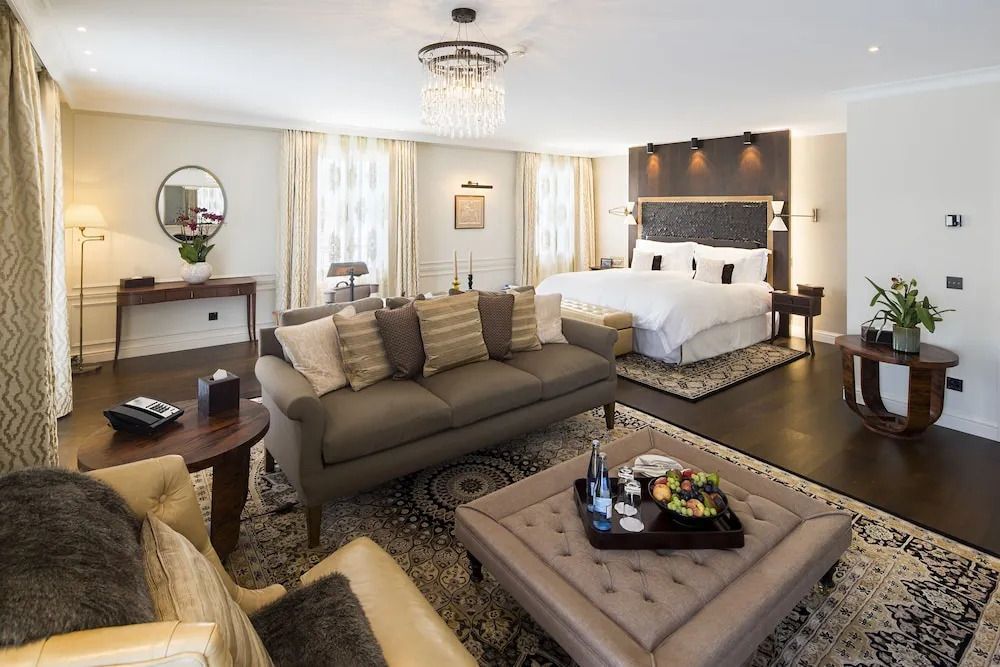 Luxuriöse Suite mit Doppelbett, eleganter Einrichtung und Sofa im Hotel Villa Honegg