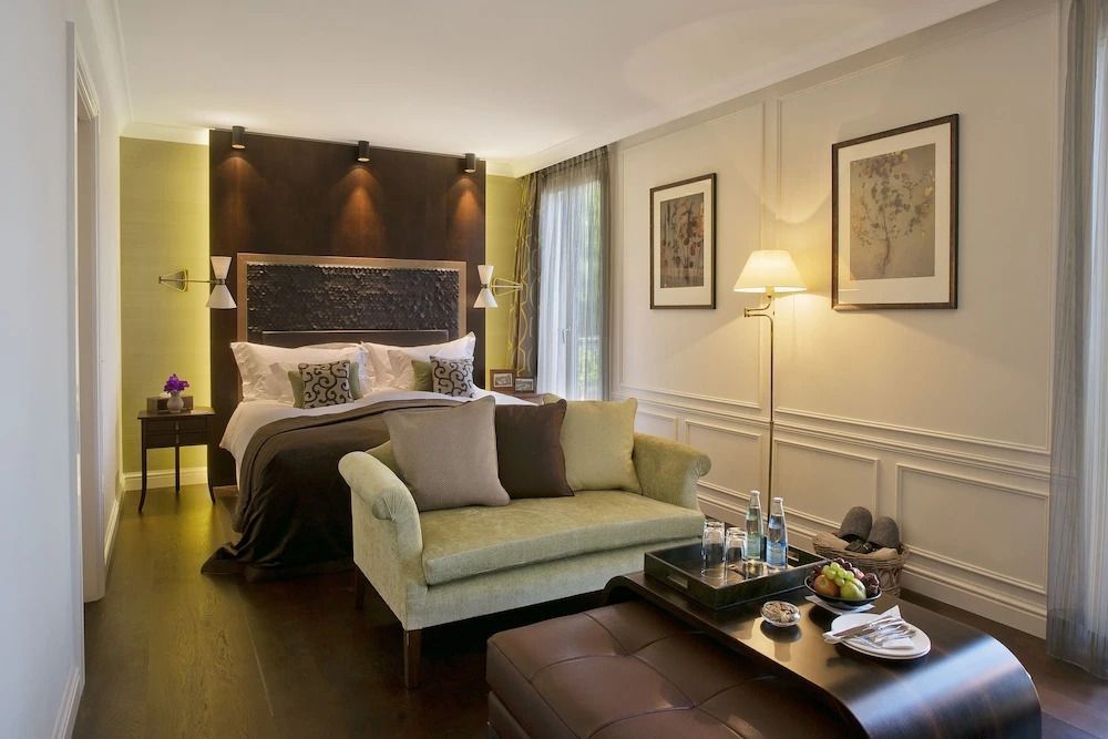Elegantes Hotelzimmer mit Doppelbett und Sofa, seitlicher Ausblick auf den Balkon