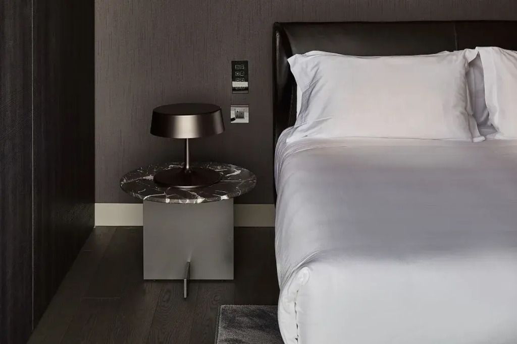 Nachttisch mit Designerlampe und Doppelbett in der Hotelsuite.