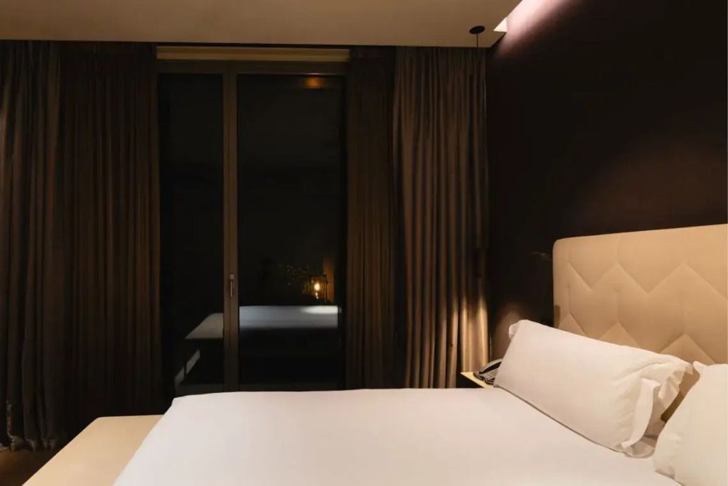 Elegantes Schlafzimmer mit Doppelbett und Balkonzugang bei Nacht