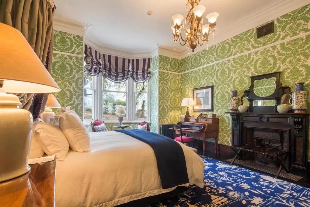 Elegantes Schlafzimmer mit grün gemusterten Wänden und luxuriöser Beleuchtung