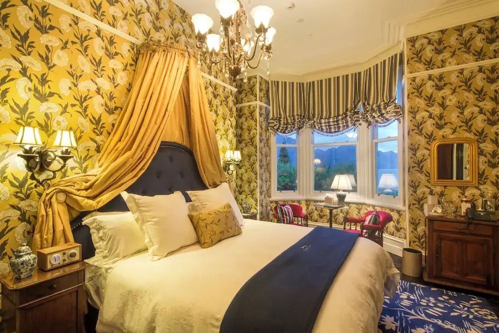 Luxuriöses Hotelzimmer mit Baldachin und großem Fenster mit Bergblick