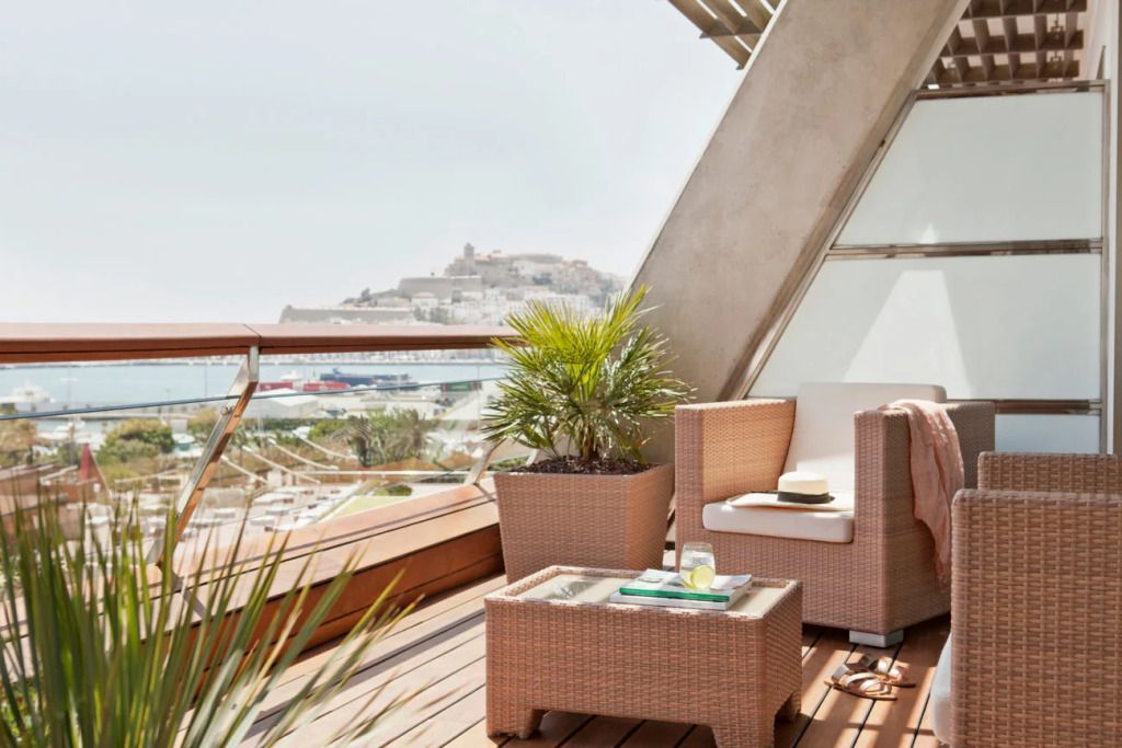 Balkon mit gemütlichen Rattanmöbeln und Blick auf die Stadtlandschaft von Ibiza
